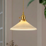 Pendant light with ribbed glass shade hanging against a neutral wall.